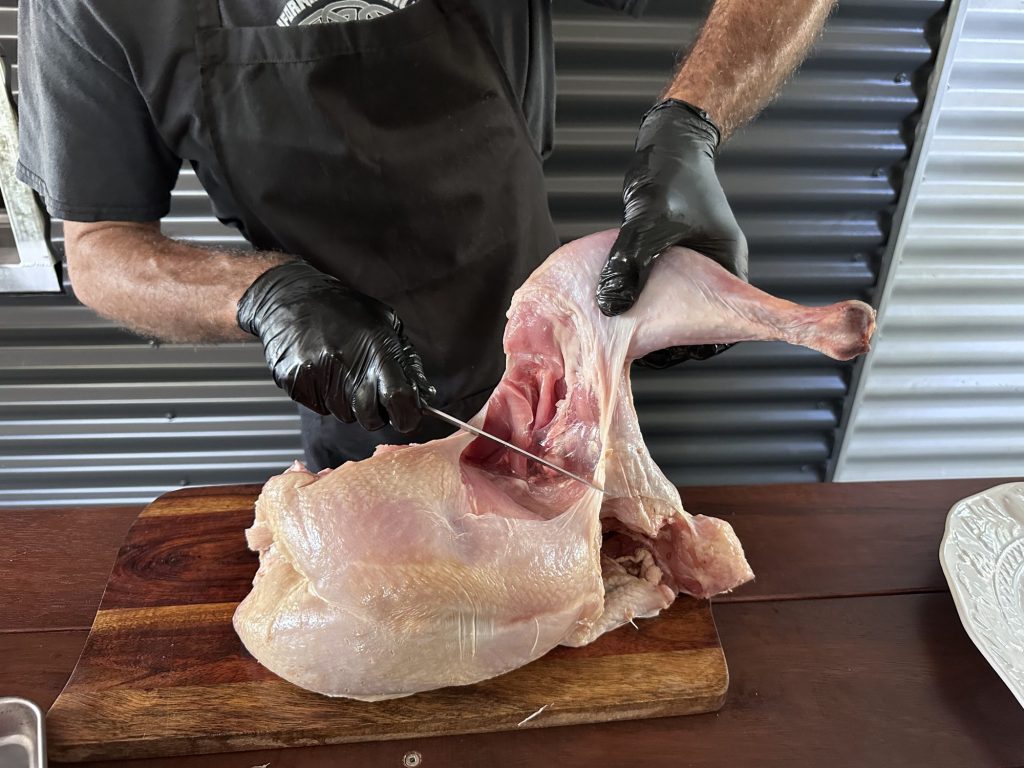 Cutting through the hip joint to take a turkey leg off the carcass