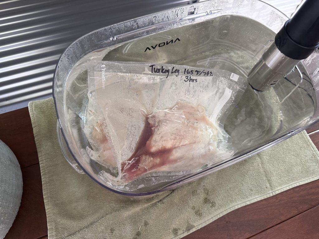 Vacuum sealed turkey leg cooking in an Anova sous vide water bath at 165F / 74C