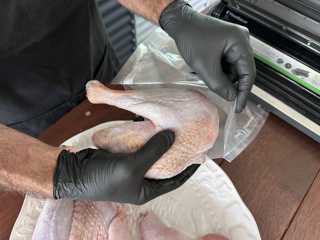 Sliding a whole raw turkey leg into a vacuum sealer bag